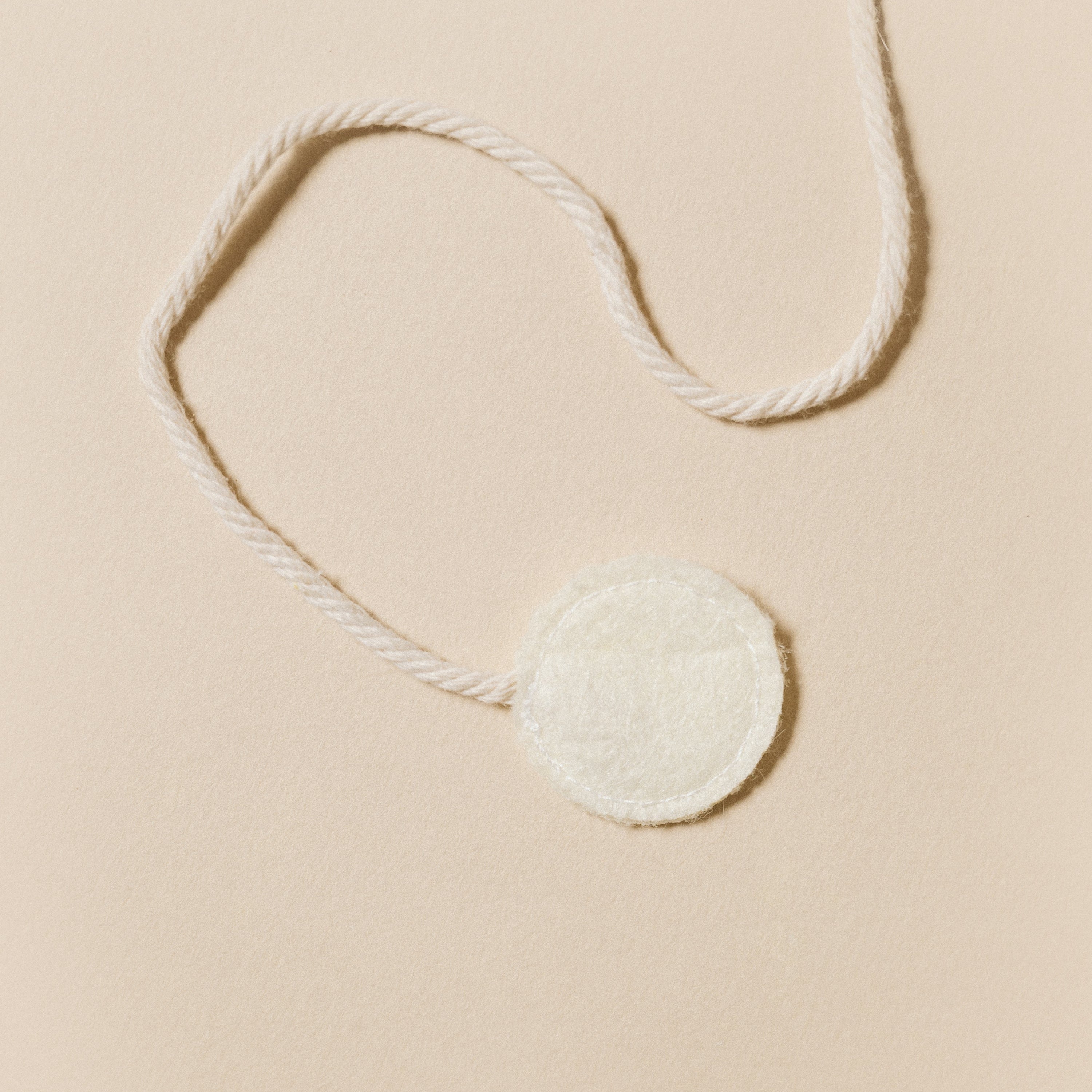 Round white patch with string on a beige background